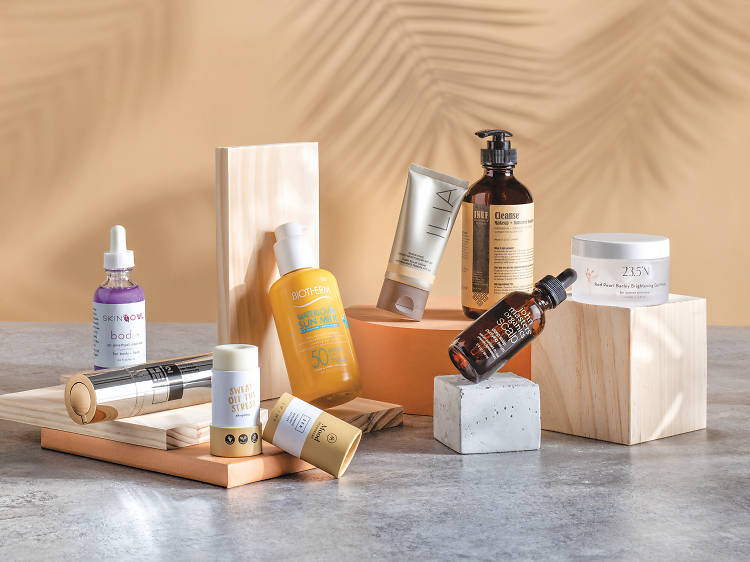 Curated lineup of premium spa skincare products — serums, cleansers, SPF, sun stick and brightening cream — arranged on wooden blocks with soft palm-leaf shadows, representing a small business's retail catalogue mapped to scan results.